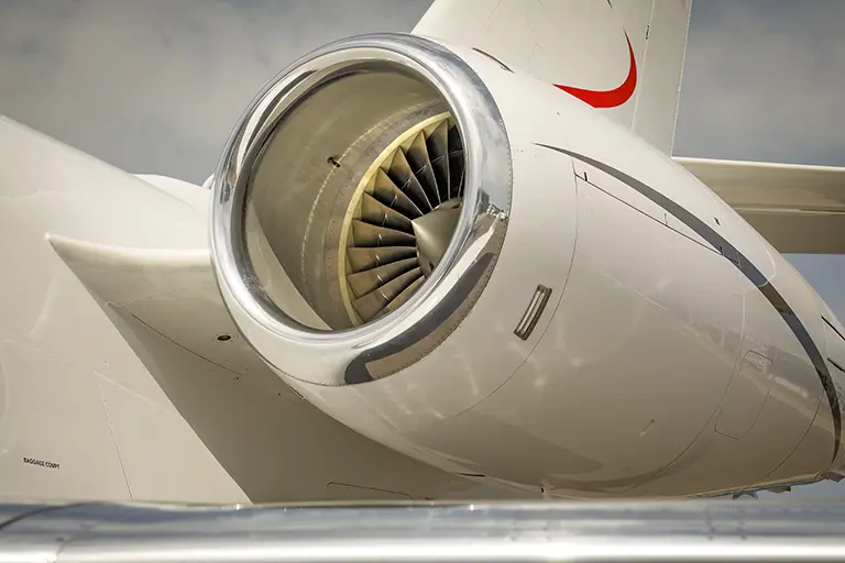 A close-up of a powerful Jetwise private jet engine, highlighting its precision-engineered fan blades. The aircraft's sleek white fuselage with a red accent reflects Jetwise's commitment to excellence in aviation.